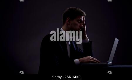 Tired business man working on laptop until late night, project management Stock Photo