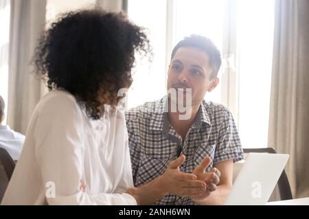 Millennial diverse colleagues talking at office workplace discussing ideas or brainstorming together, young multiracial workers speak during work brea Stock Photo