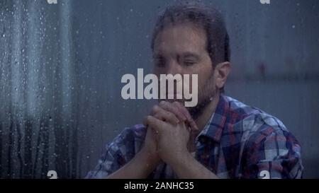 Adult man praying, asking God for mercy and strength, rainy weather, faith Stock Photo
