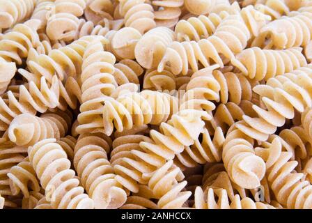 Uncooked brown wholegrain wheat bronze cut fusilli pasta creates a food background of texture and patterns. Stock Photo