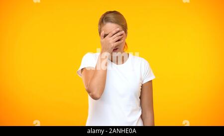 Stressed woman showing face palm gesture, covering eyes by hands, disappointment Stock Photo