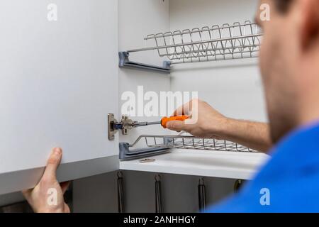 handyman doing kitchen cabinet hinge adjustment Stock Photo