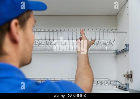 furniture service worker installing kitchen cabinet dish rack Stock Photo