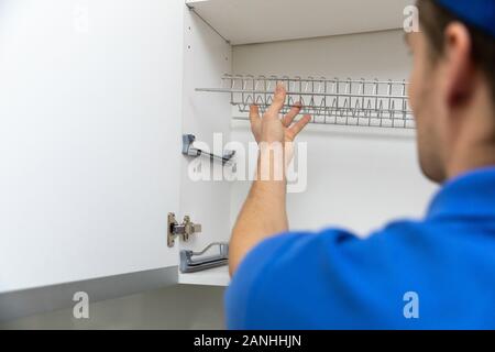 furniture service worker installing kitchen cabinet dish rack Stock Photo
