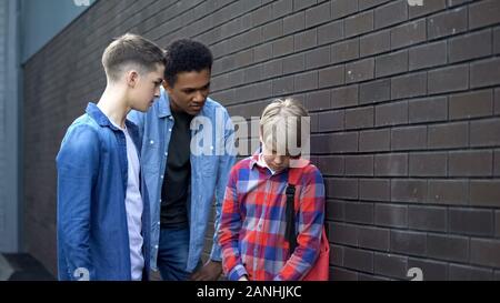 Cruel high school students bullying junior boy, verbal abuse, intimidation Stock Photo