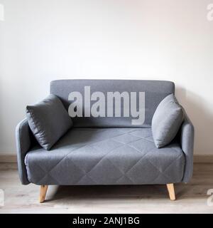 Copy space. Gray sofa with pillows in the style of the sixties in the interior. Stock Photo