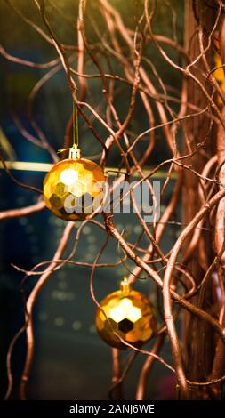 Stylish golden geometric balls as a Christmas decoration on wooden rounded branches of a vine near the facade of the building. Stock Photo