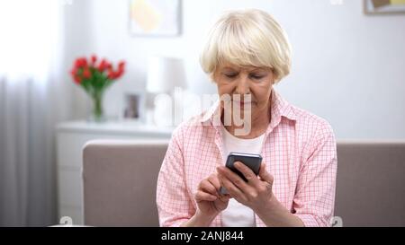 Serious elderly woman learning using new smartphone, technology for old people Stock Photo
