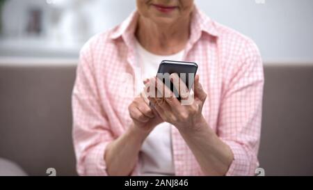 Smiling aged woman using smartphone, application for elderly people, technology Stock Photo