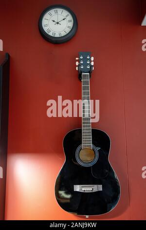 Acoustic guitar, hanging on the red wall Stock Photo