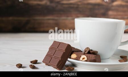 pieces of chocolate with hazelnuts and coffee beans on a brown tablecloth Stock Photo