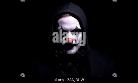 Crazy man in spooky clown mask staring at camera, murder or robbery threat Stock Photo