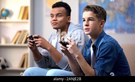 African-american and caucasian teenagers playing video games, gaming addiction Stock Photo