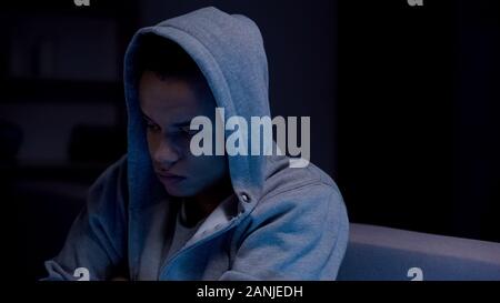 African-american teen boy sitting in dark room suffering depression, loneliness Stock Photo