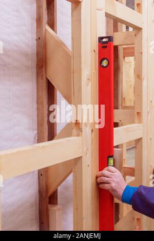 Quality control of the construction of wooden building structures of a frame house. Measurement of vertical deviation of installed structures. Stock Photo