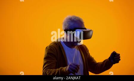 Male pensioner in virtual reality goggles playing videogame, modern technologies Stock Photo