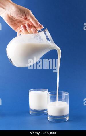 Homemade fermented beverage kefir pouring in a glass on a trendy blue background, concept of natural fermented food and intestinal health Stock Photo