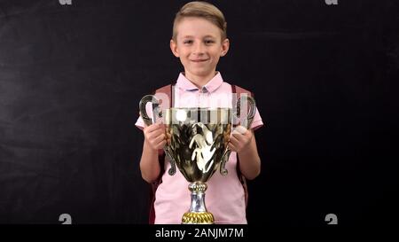 Happy schoolboy holding bowl award, winning sports tournament, successful child Stock Photo