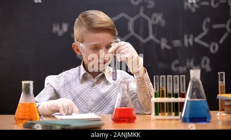 Schoolboy looking at chemical substance in test tube, chemistry lesson, hobby Stock Photo