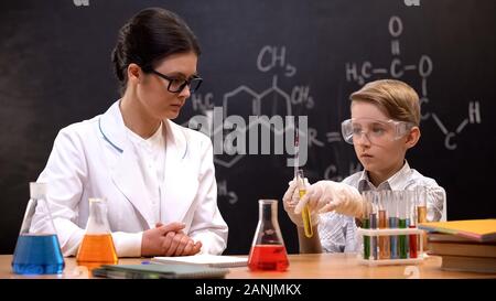 Chemistry teacher watching schoolboy taking liquid into pipette, private lesson Stock Photo