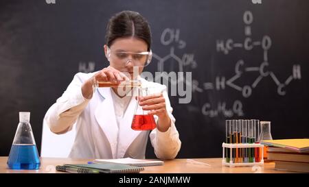 Chemistry student mixing liquids in scientific laboratory, conducting experiment Stock Photo