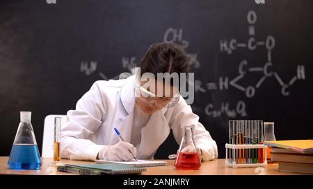 Laboratory worker writing down chemical research results, conducting experiments Stock Photo