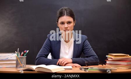 Tired overworked female teacher looking to camera, troubles at work, burnout Stock Photo