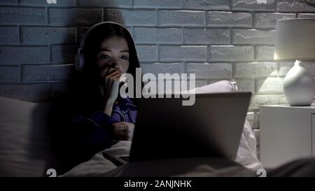 Woman in headphones watching drama movie, worrying for characters, free time Stock Photo