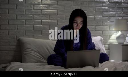 Extremely tired asian woman working on laptop at night in bedroom, workaholic Stock Photo