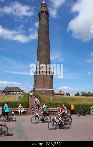 Cyclists cycling past Borkum Great Light also know as Borkum new lighthouse Stock Photo