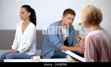 Couple turned from each other sitting at psychology therapy working on relations Stock Photo