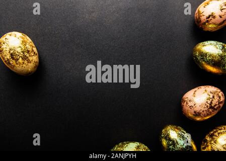 Natural Golden Speckled Easter Eggs of pastel colors on black background. Happy Easter card concept, minimalistic design, copy space Stock Photo