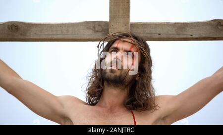 Jesus suffering on cross, looking in sky praying to god to forgive sin people Stock Photo