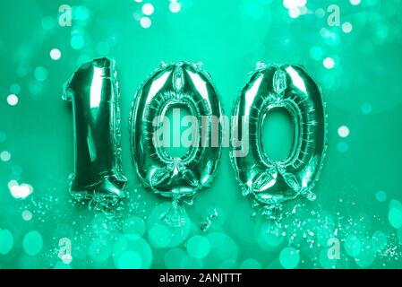 Balloon Bunting for celebration Happy 100th Anniversary made from Silver Number Balloons on green background with bokeh lights. Holiday Party Decoration or postcard concept with top view Stock Photo