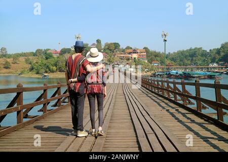 Happy Couple Walking on the 447 Metre-long Wooden Mon Bridge, the Iconic Landmark of Sangkhlaburi District in Thailand Stock Photo