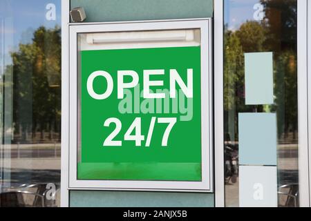 Close-up Of Green Open 24/7 Information Board Hanging On Glass Door Stock Photo