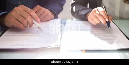 Close-up Of Two Businesspeople Working On Contract Paper Stock Photo