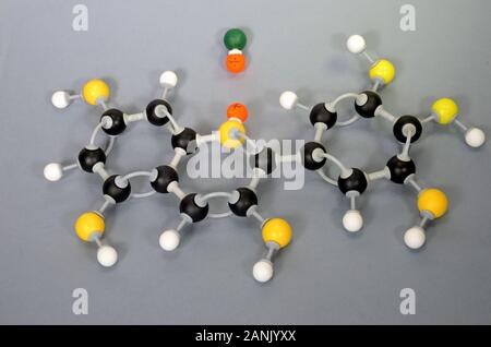 Molecule model of Paraffin. White is Hydrogen, black is Carbon, yellow is Oxygen and green is Chlorine. The orange spheres represent charges in a coor Stock Photo
