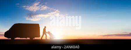 Silhouette Of Delivery Courier With Cardboard Boxes On Trolley Near The Van At Sunset Stock Photo