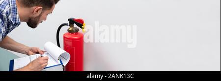 Close-up Of Technician Using Digital Tablet Checking Fire Extinguisher Stock Photo