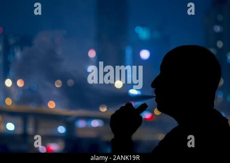 Man with electronic cigarette and smoke vapping with city bokehlights background help quit smoking tobacco Stock Photo