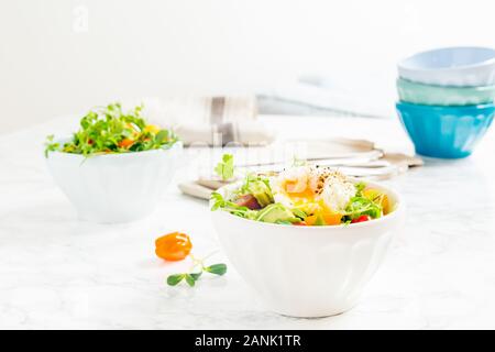 Mixed baby greens and cherry tomatoes salad with avocado and poached egg in bowl. Superfood snack concept. Horizontal Stock Photo