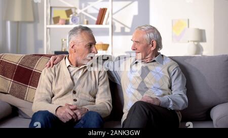 Two old friends talking having fun sitting on sofa, positive mood, conversation Stock Photo