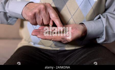 Aged man counting coins in open palm, low income, social insecurity, close-up Stock Photo