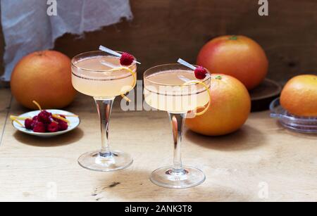 Champagne cocktail with grapefruit juice, garnished with zest and raspberries. Rustic style. Stock Photo