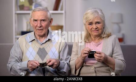 Upset aged couple showing empty purses on camera, social reform, retirement Stock Photo