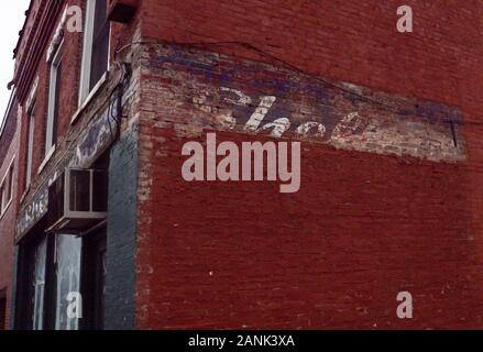 Outer wall of a red brick building with old, pealing advertisement Stock Photo