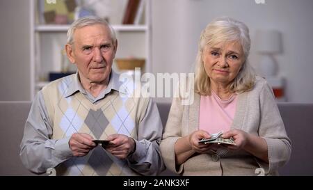 Desperate old pensioners holding dollars, social insecurity, lack of money Stock Photo