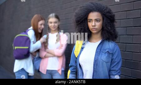 Two female students laughing at curly afro-american teenager, school bullying Stock Photo