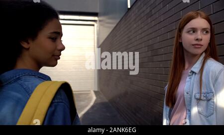 Young females with backpack looking back walking college campus, attention Stock Photo